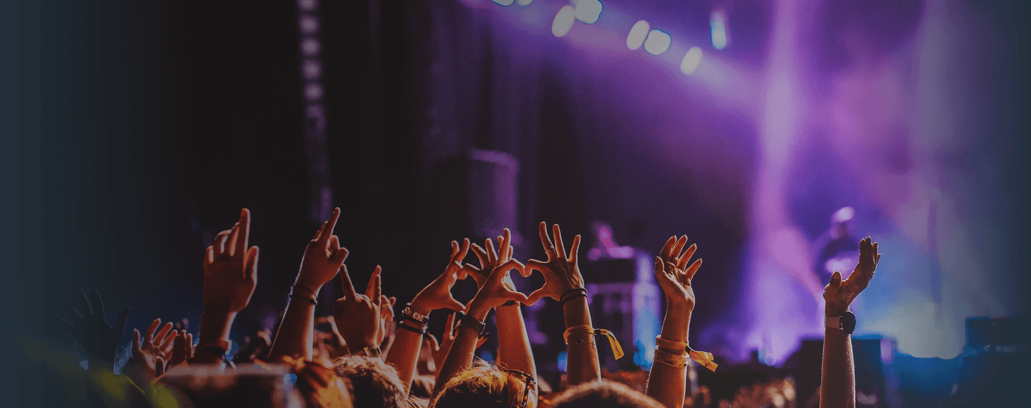 Crowd raises hands in excitement at live music performance. Overlaid is the German word "Konzert" with its English translation, "concert".
